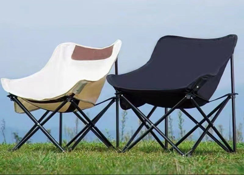 Two portable folding chairs on grass with a clear sky background